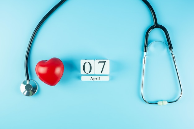 Foto vista dall'alto stetoscopio, a forma di cuore rosso e calendario del 7 aprile. giornata mondiale della salute