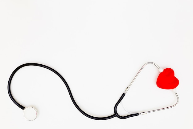 Top view of stethoscope and red heart on white background