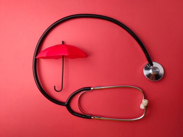 Top view stethoscope and red umbrella on a red background