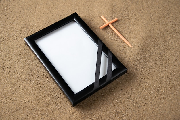 Top view of stick cross with picture frame on the sand