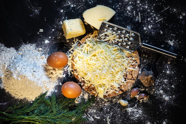 Vista dall'alto di una natura morta del processo di produzione di palline di formaggio con aglio e aneto su sfondo nero
