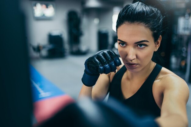 Top view of strong brunette attractive female trainer punching a bag with kickboxing gloves in the gym workout Sport fitness lifestyle and motivation concept