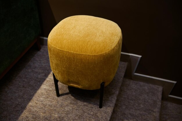 Top view of a stylish velour yellow footstool ottoman in the furniture design showroom