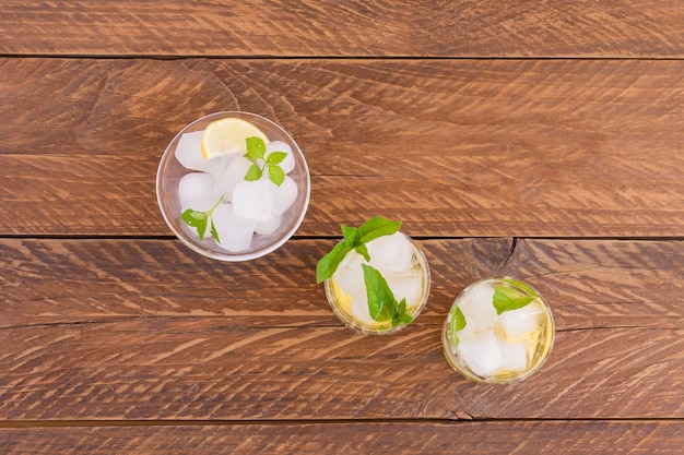 Top view of summer cooling beverages on wooden table. Coolig fresh lemonade with lime, lemon, mint leaves and ice.