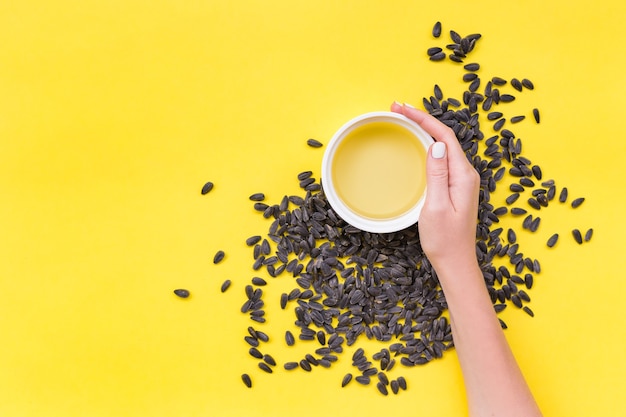 Top view of sunflower seeds and oil, photo on top of yellow surface