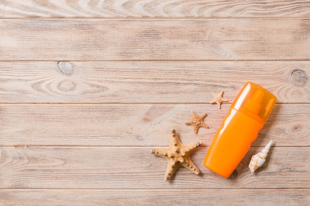 Top view of sunscreen bottle with starfish on wooden board background with copy space. flat lay concept of summer travel vacation.