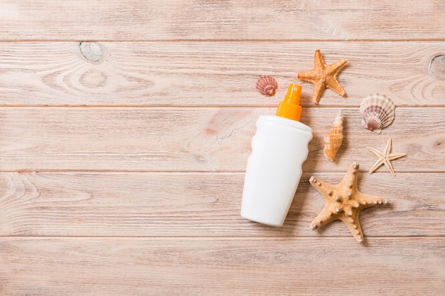 Top view of sunscreen bottle with starfish on wooden board background with copy space. flat lay concept of summer travel vacation.