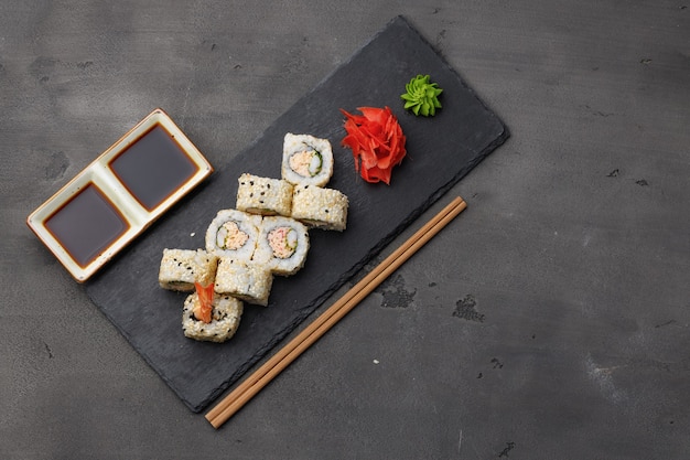 Top view of sushi roll with sesame on dark grey