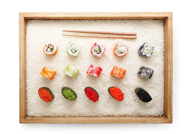 Top view on sushi rolls and gunkan with colored caviar near chopsticks in wooden frame on white rice background and texture, isolated