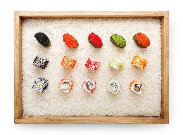 Top view on sushi rolls and gunkan with colored caviar in wooden frame on white rice background and texture copy space, isolated