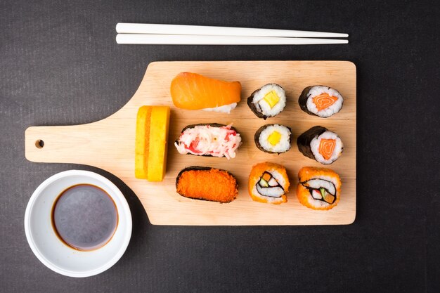 Top view of Sushi set on wooden tray with chopsticks and sauce on black background, Japanese food.