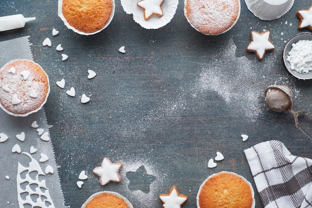 Top view of the table with sugar-sprinkled muffins, fondant icing and Christmas star cookies 