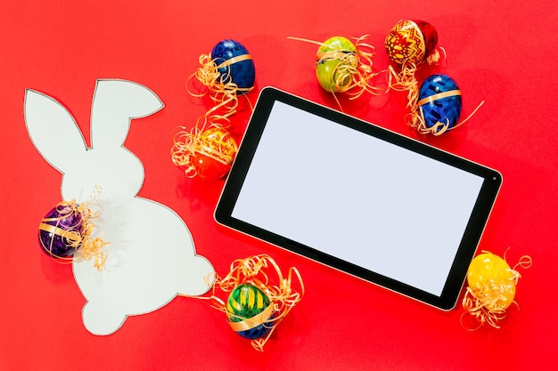 Top view of tablet and easter eggs paper rabbit