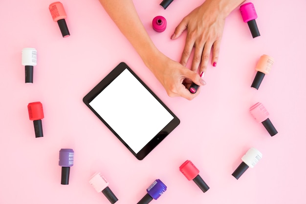 Photo top view tablet surrounded by nail polish