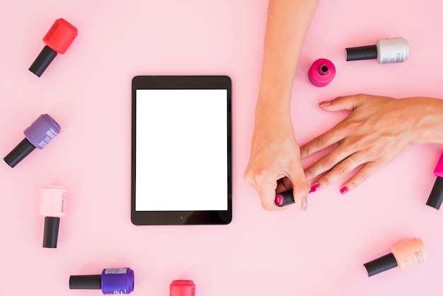 Top view tablet surrounded by nail polish