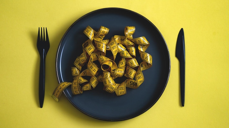Photo top view of tape measurement on a black plate looking like food pastadiet concept healthy lifestyle
