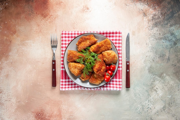 Top view tasty chicken wings with greens and tomatoes on light surface