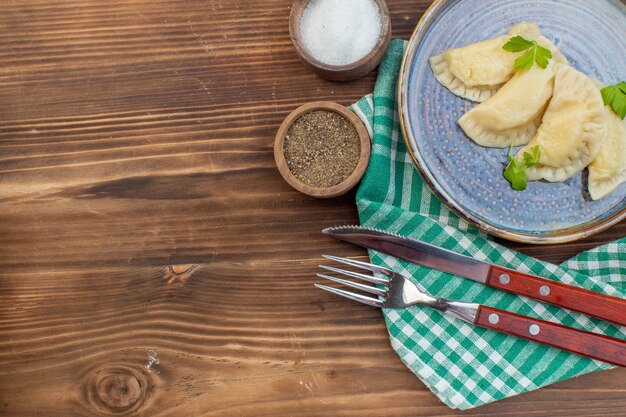 Фото Вид сверху вкусные горячие пирожки с приправами на коричневом деревянном столе приготовление еды пирог печь пирог испечь кухню тесто