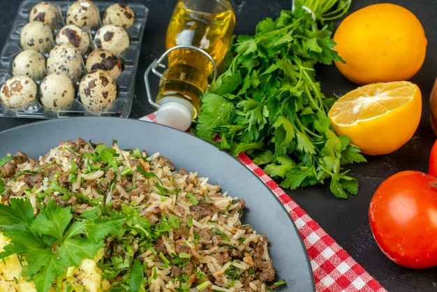 赤いストリップタオルの上のプレートに肉マッシュポテトと黒の背景に新鮮な野菜レモン落ちたオイルボトルとおいしい夕食の上面図