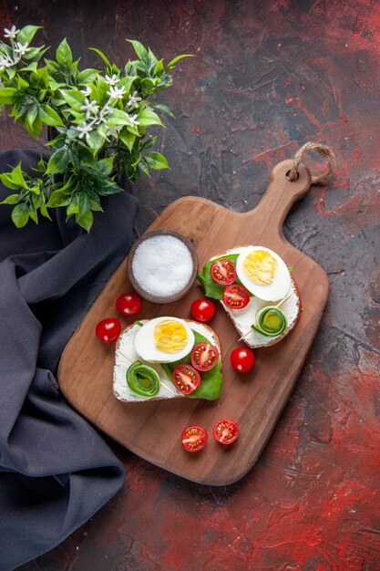 top view tasty egg sandwiches with red tomatoes on cutting board dark red background lunch sandwich food bread burger snack toast