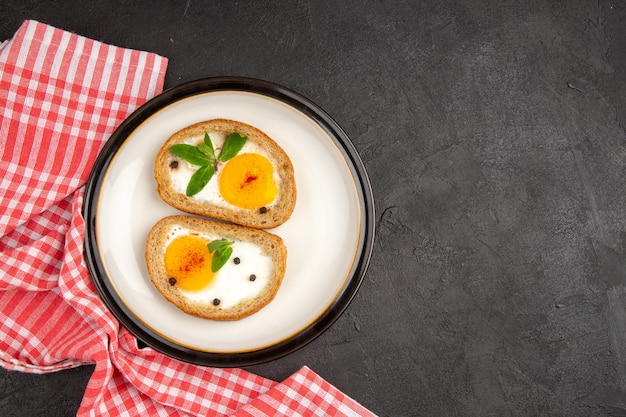 Фото Вид сверху вкусные яичные тосты внутри тарелки на темном фоне еда хлеб омлет еда обед утро завтрак чай