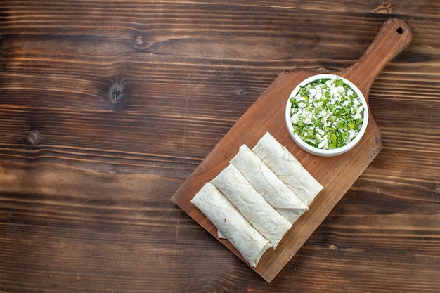 top view tasty pitas with greens on cutting board brown table