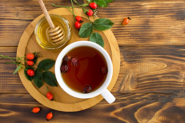 Top view of tea with dogrose and honey on the wooden cutting board