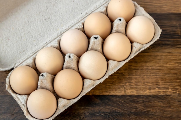 Top view ten chicken eggs in a cardboard tray on the table