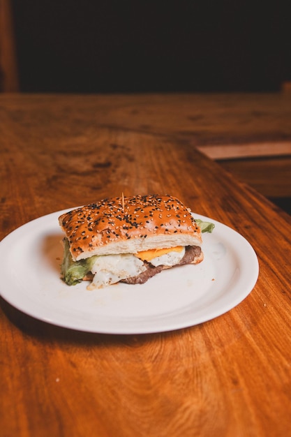 Top view of a tenderloin sandwich with fried egg and lettuce on a wooden table