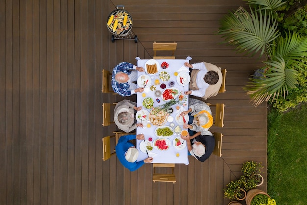 Top view of terrace with table full of food and seniors sitting at it