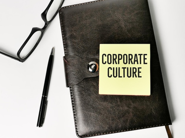 Top view text CORPORATE CULTURE written on sticky note with a pen and diary book.