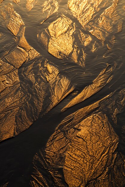 Top view of textured lines background on sand in the beach created by the low tide.