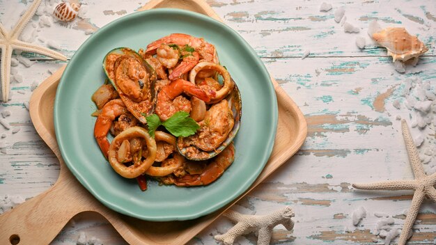 Foto vista dall'alto del cibo tailandese, curry saltato in padella di pesce in polvere sul piatto in ceramica verde sulla tavola di legno