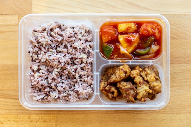 Top view of Thai styled organic Sweet and Sour fried with pork and rice berry in food grade box.