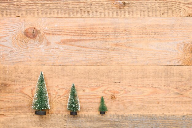 Top view on three little Christmas trees on wooden background