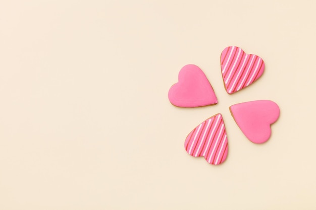 Top view on three little gingerbread cookies in shape of hearts on light yellow background