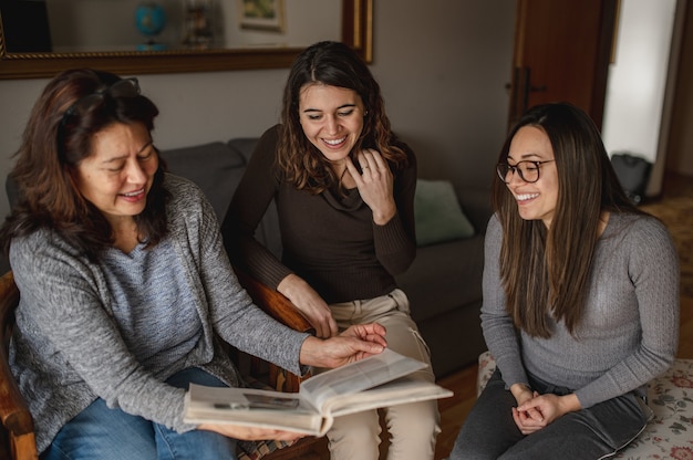 Top view three women, mother and daughters looking a book of memories. Togetherness, family concept.