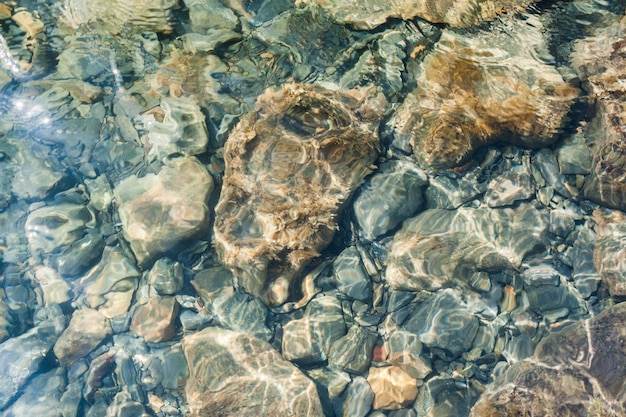 Top view through clear sea water to different sizes boulders. 