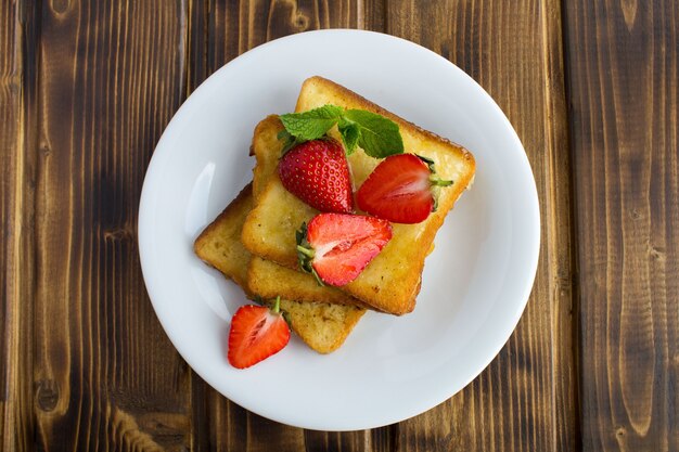 Top view of toasts with strawberries in the white plate