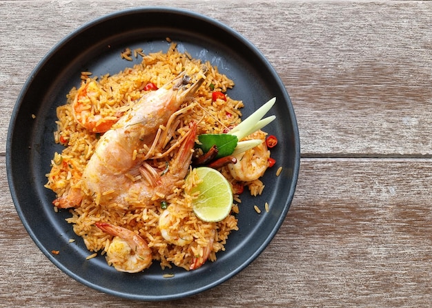 Top view Tom Yum Fried Rice with prawns on a wooden background