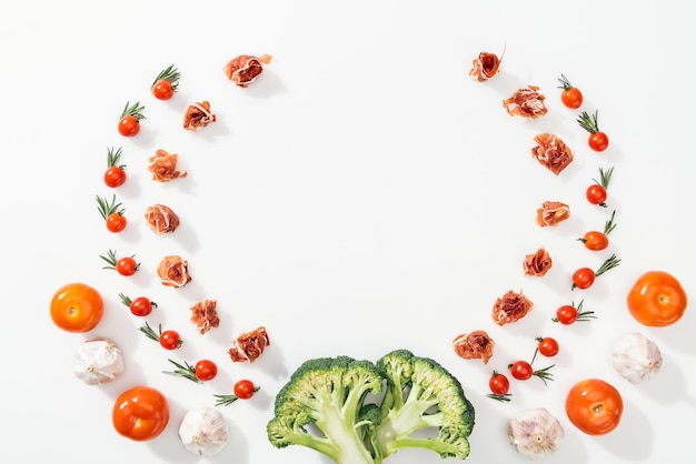 Top view of tomatoes leaves prosciutto broccoli and garlic with copy space