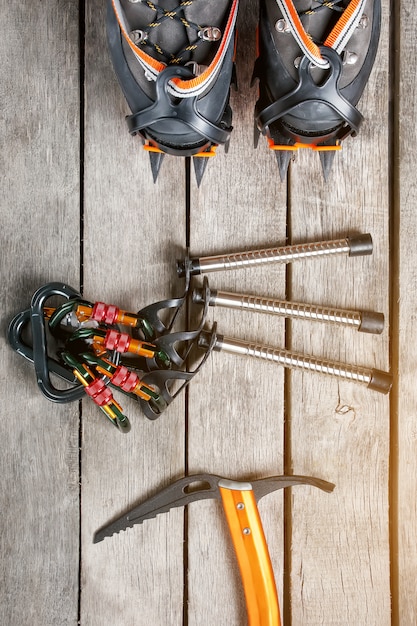 Top view of tourist equipment for a mountain trip on a rustic light wooden floor, sunlight