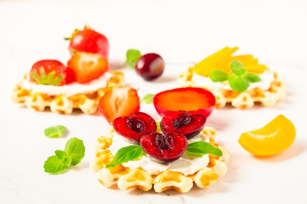 Top view of traditional Belgian waffles with soft cheese, fruits and berries