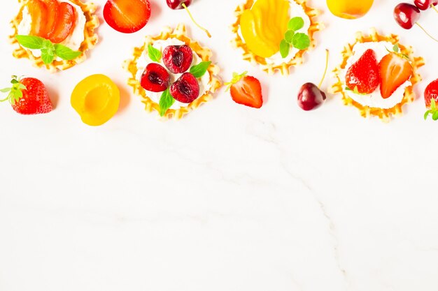 Photo top view of traditional belgian waffles with soft cheese, fruits and berries