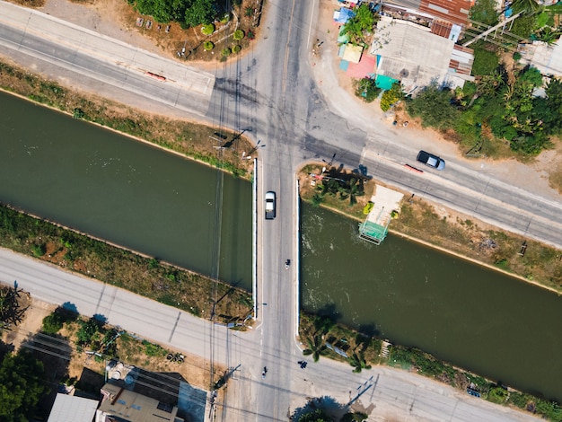 Top view of traffic on intersection road across the bridge on the canal in rural village