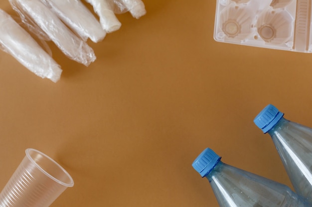 Vista dall'alto bottiglie di plastica trasparente e confezioni di plastica su sfondo marrone chiaro