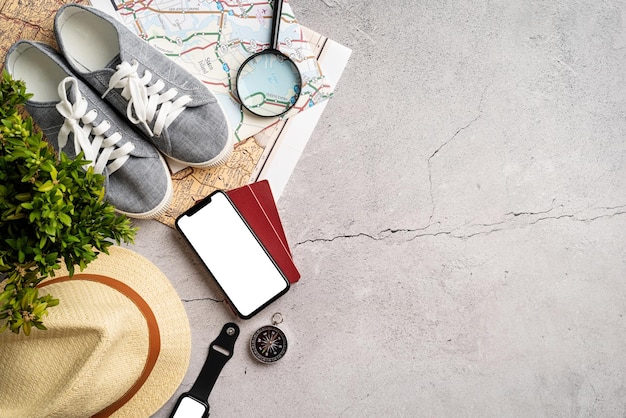 Top view travel accessories with shoes map smartphone with mockup screen hat Tourist essentials