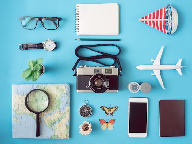 Foto vista dall'alto concetto di viaggio con pellicole per fotocamere retrò, telefono, mappa, passaporto, bussola e attrezzatura del viaggiatore sulla superficie blu, elementi essenziali per il turismo, effetto tono vintage