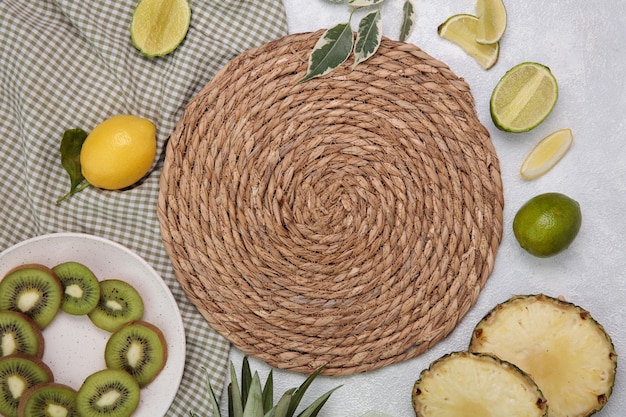 Foto vista dall'alto del sottopentola per piatti caldi con kiwi e lime al limone e fette di ananas su tela a quadri su sfondo bianco