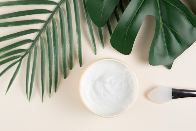 Photo top view of tropical leaves and  body cosmetics